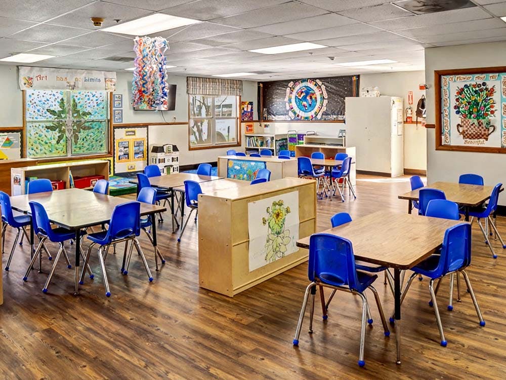 Classroom with multiple small tables and blue chairs
