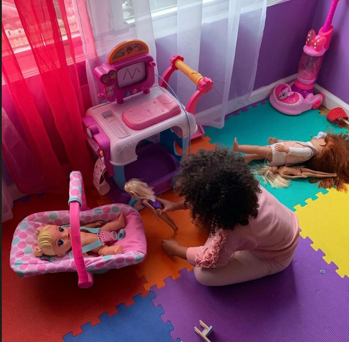 Child playing with dolls and toys on a colorful floor