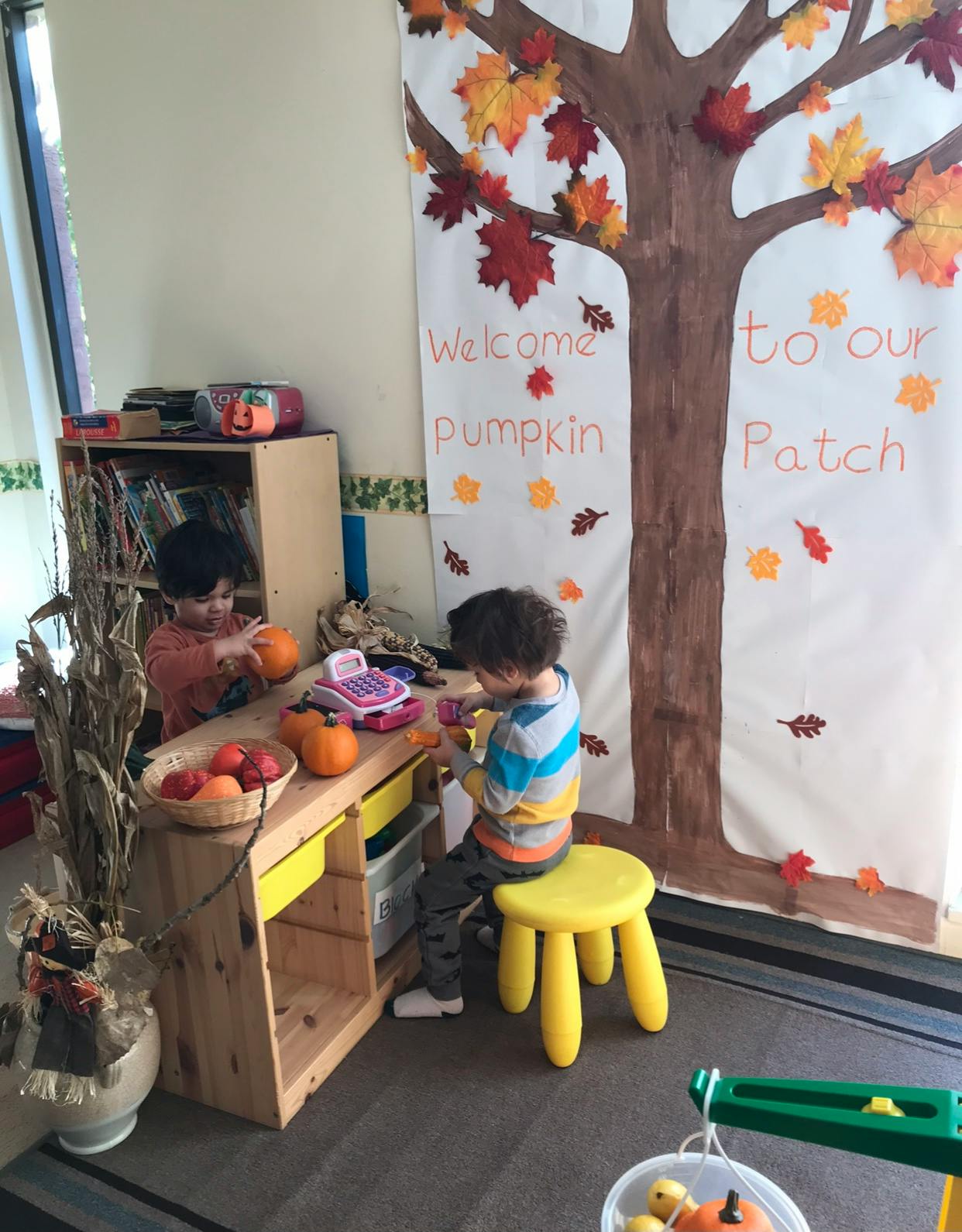 Two children playing with pumpkins and a toy cash register