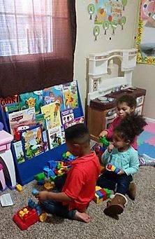 Three children playing with toys on a carpeted floor