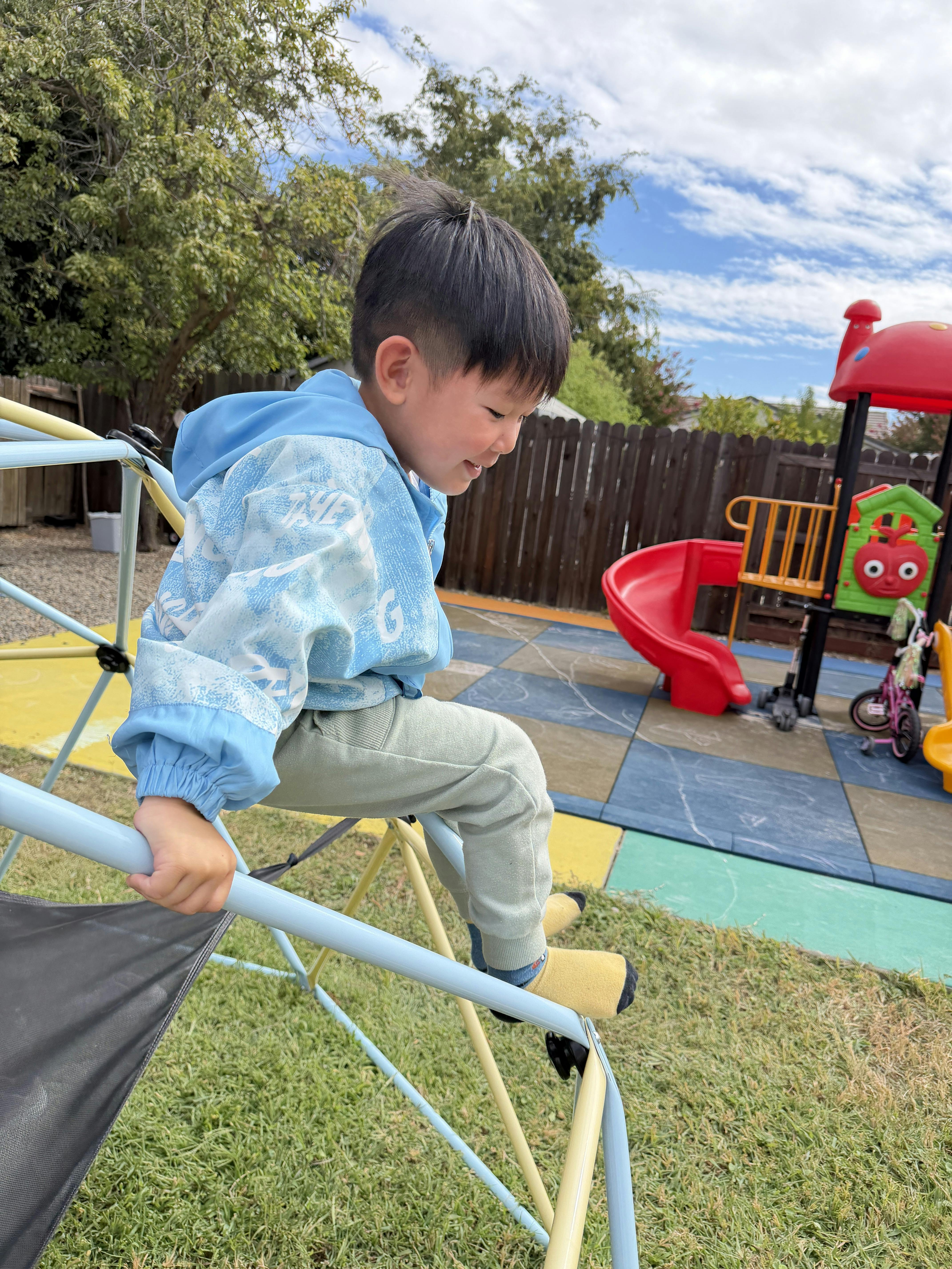 Child climbing on a metal dome structure at a playground