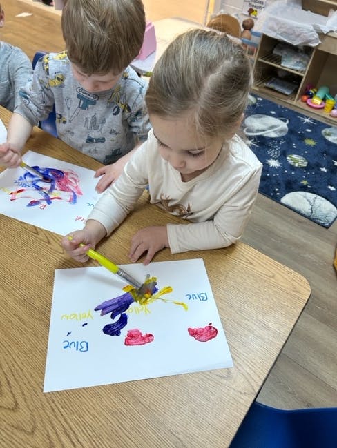 Children painting with brushes in a classroom