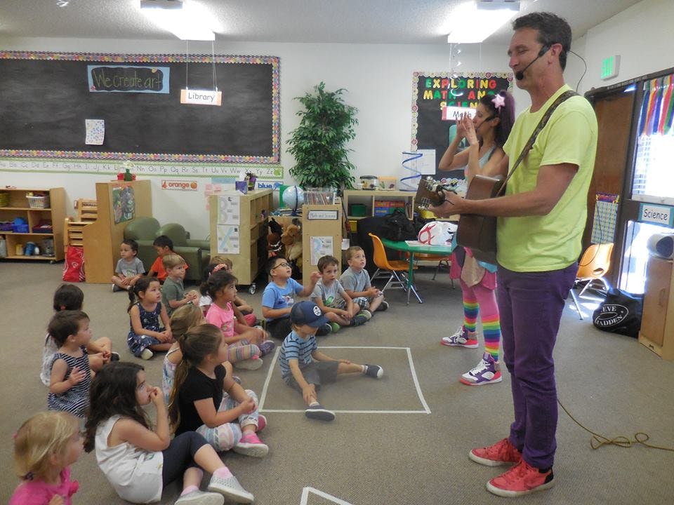 Adults with instruments performing for children in a classroom