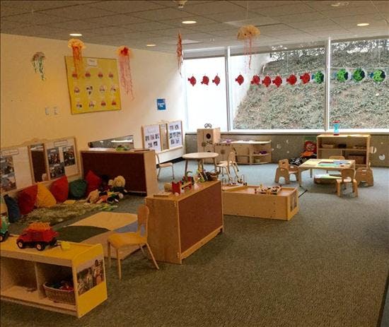 Empty classroom with small tables, chairs, and shelves