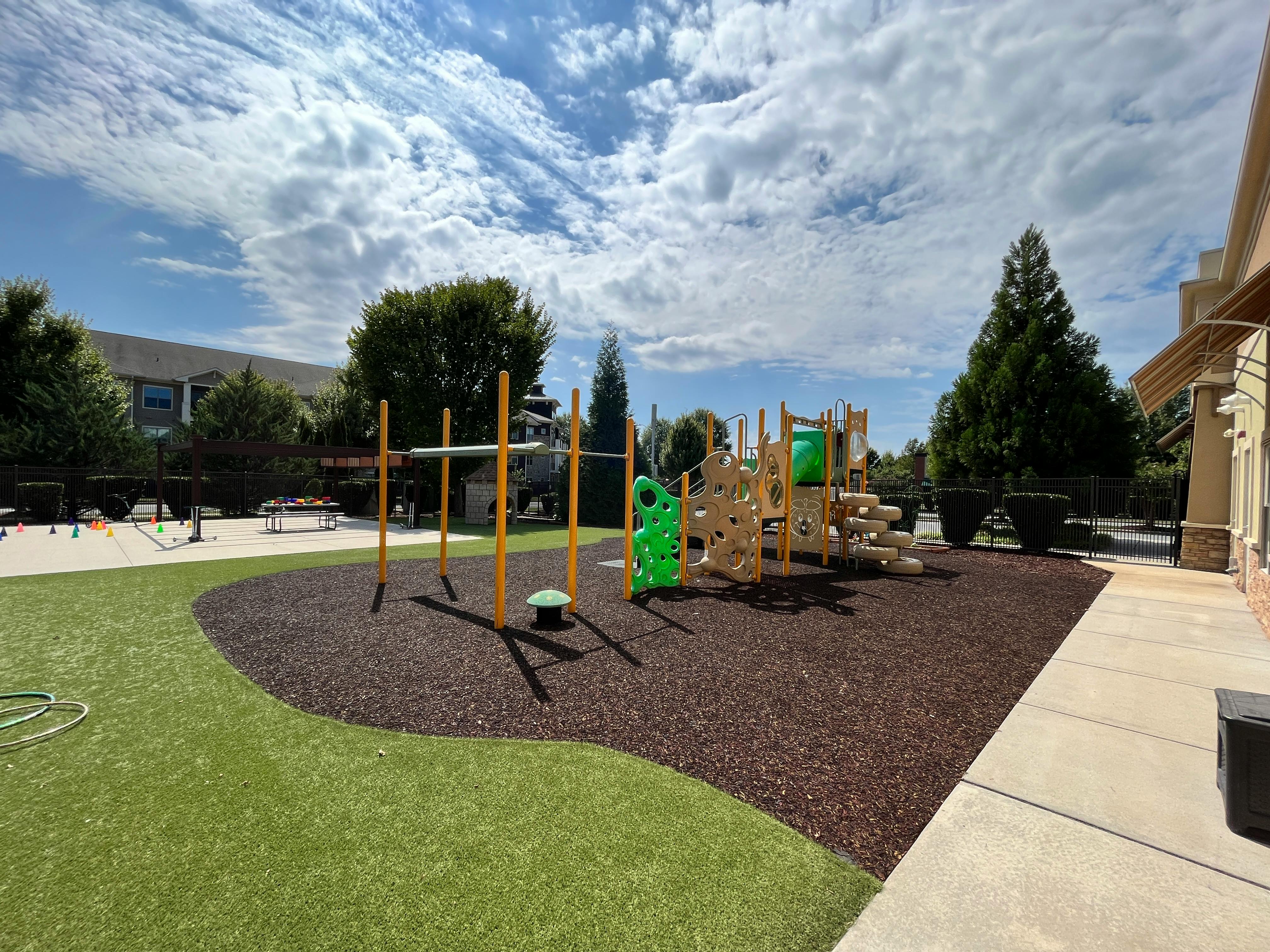 Playground with climbing structures and monkey bars on artificial turf and wood chips