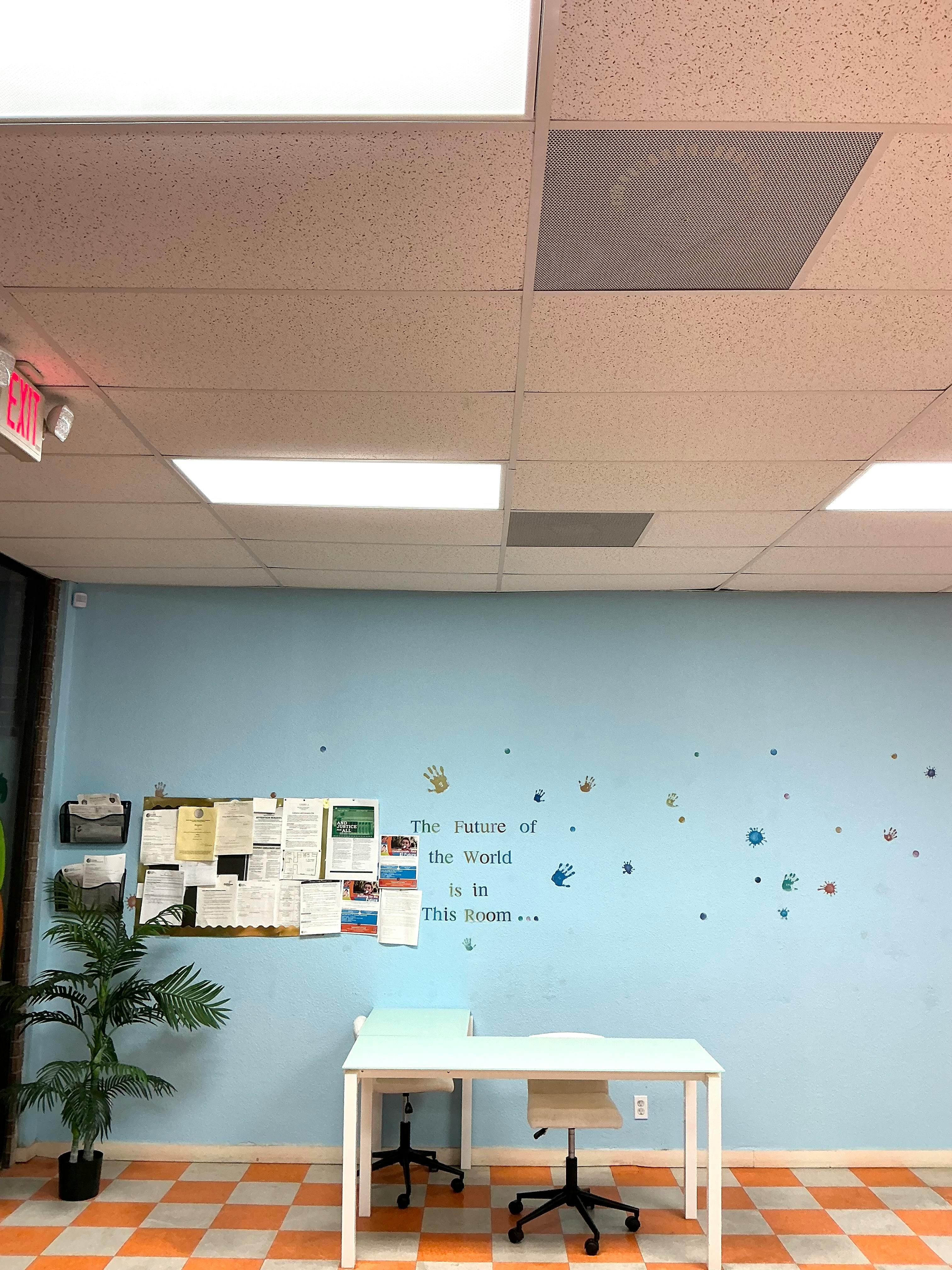 Desk and chairs in a room with a bulletin board and wall text