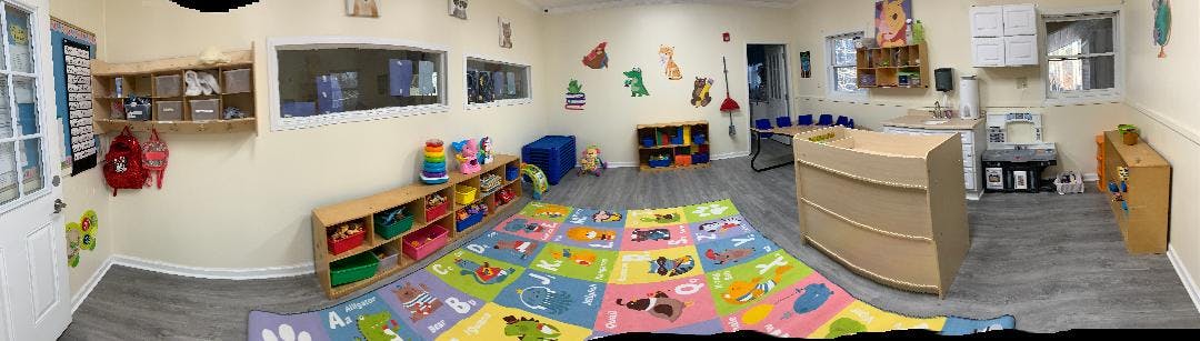 Playroom with colorful rug, shelves with toys, and small furniture