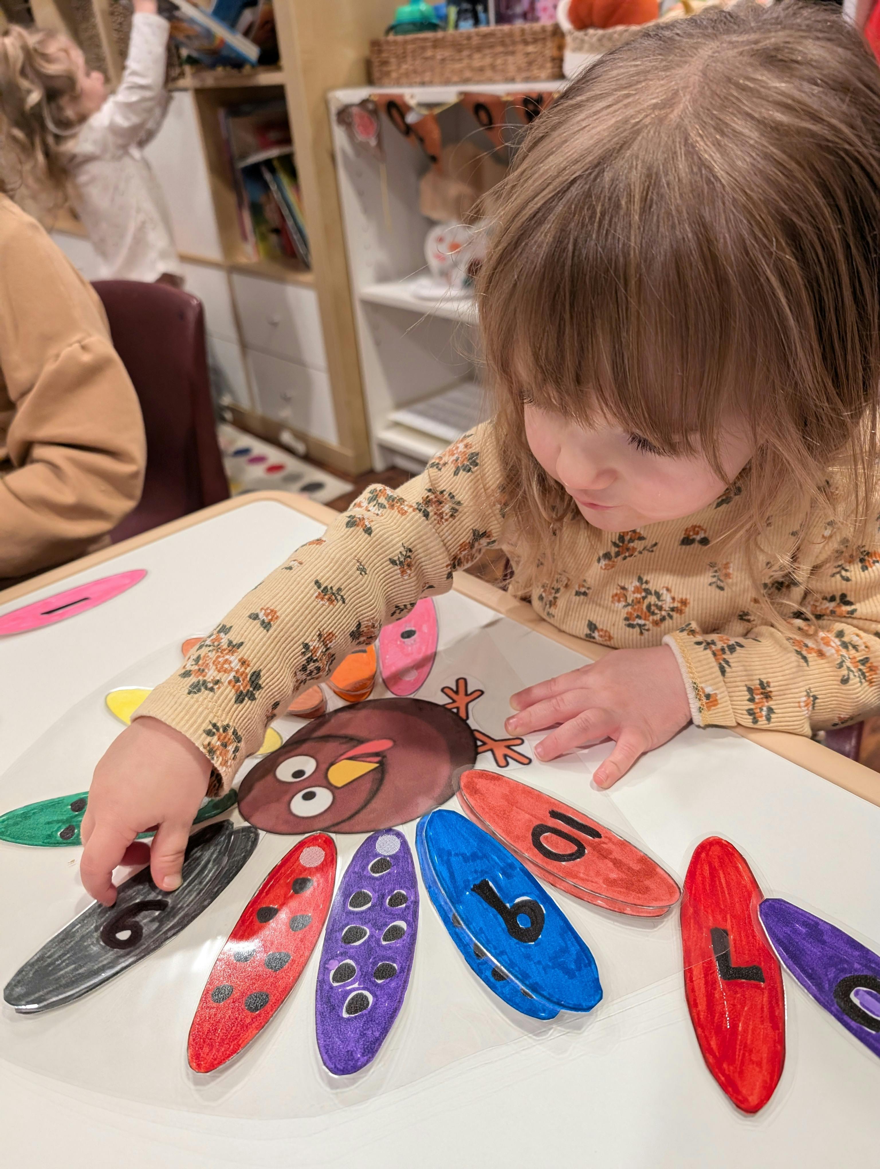Child placing a numbered feather on a paper turkey