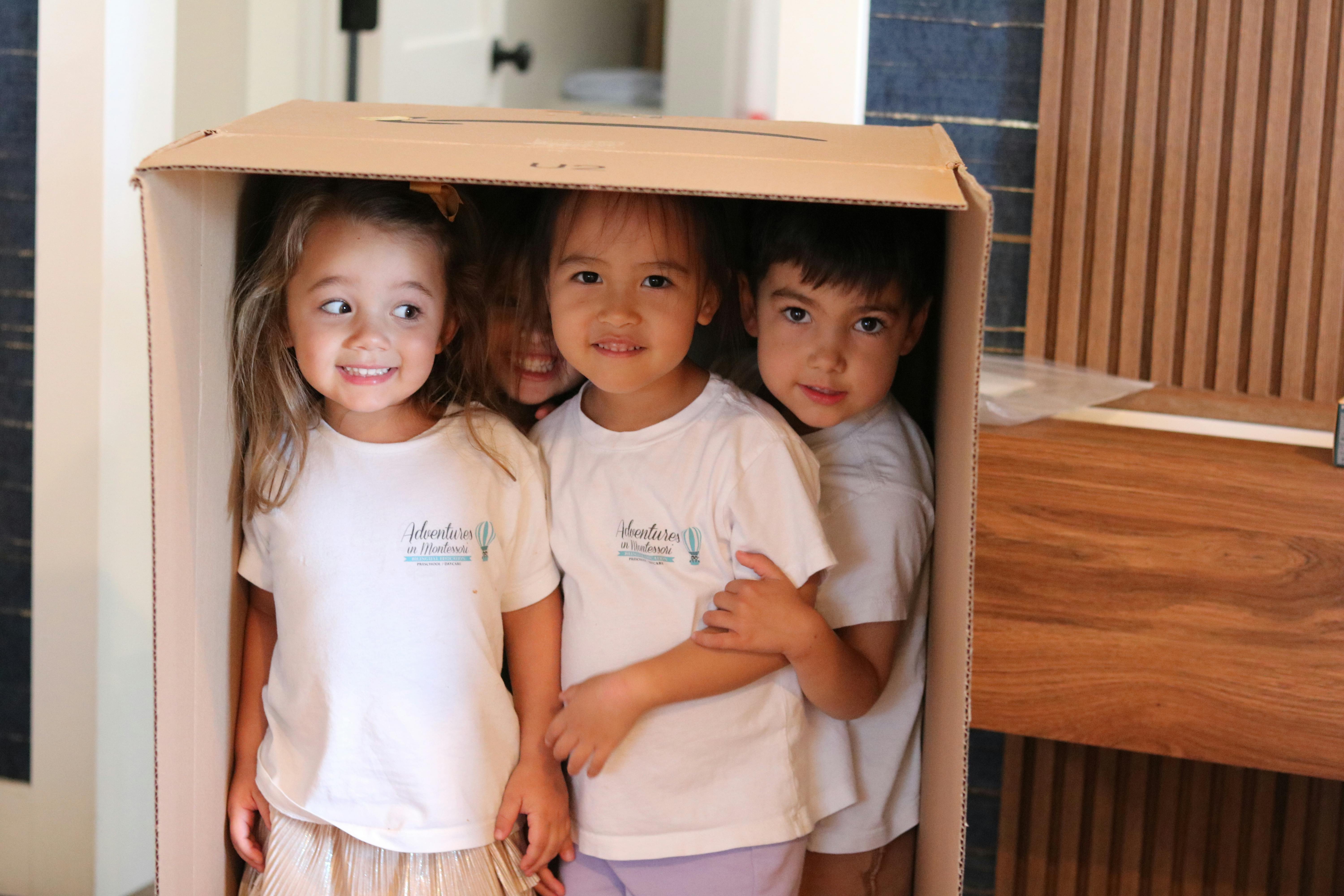 Four children standing inside a large cardboard box