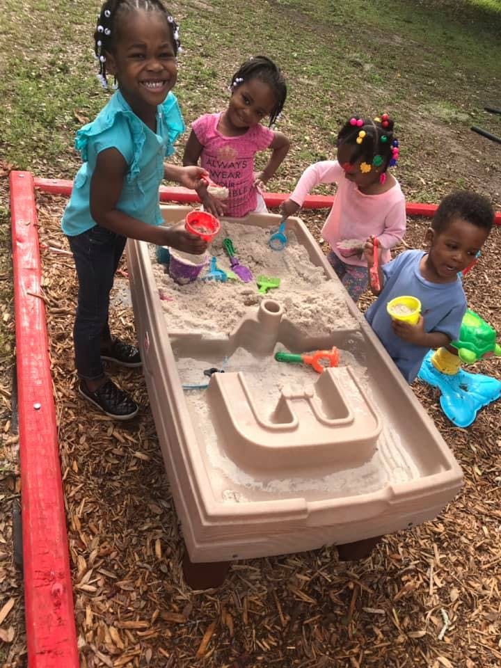 Children playing in a sand and water table outdoors