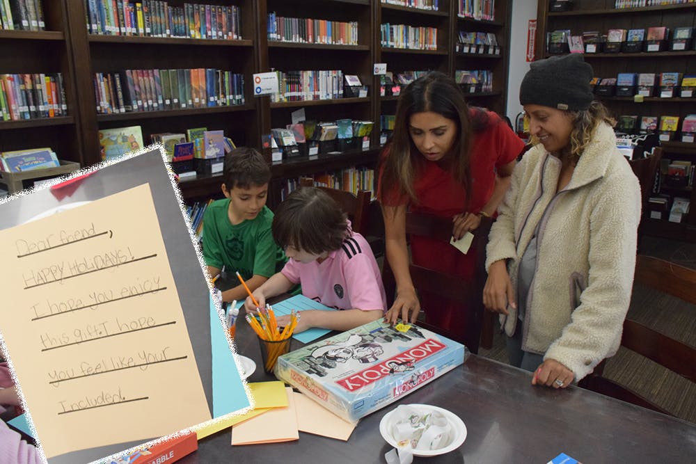 Adults and children gathered around a table with a Monopoly board game