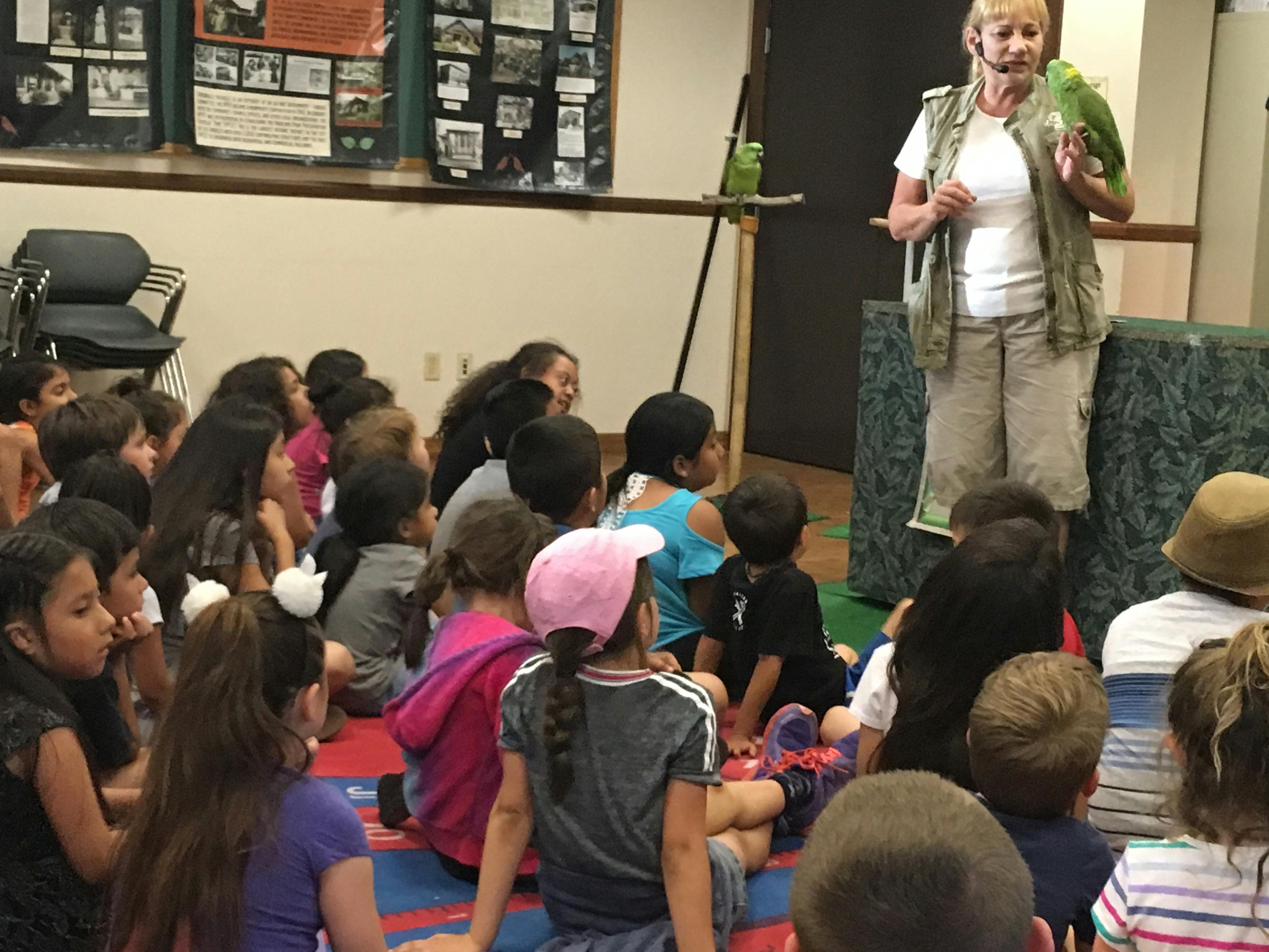 Person with a parrot on their arm speaking to a group of children