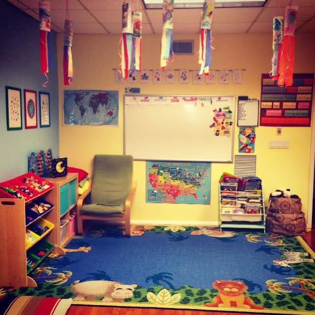 Classroom with a whiteboard, maps, and a blue rug with animal designs