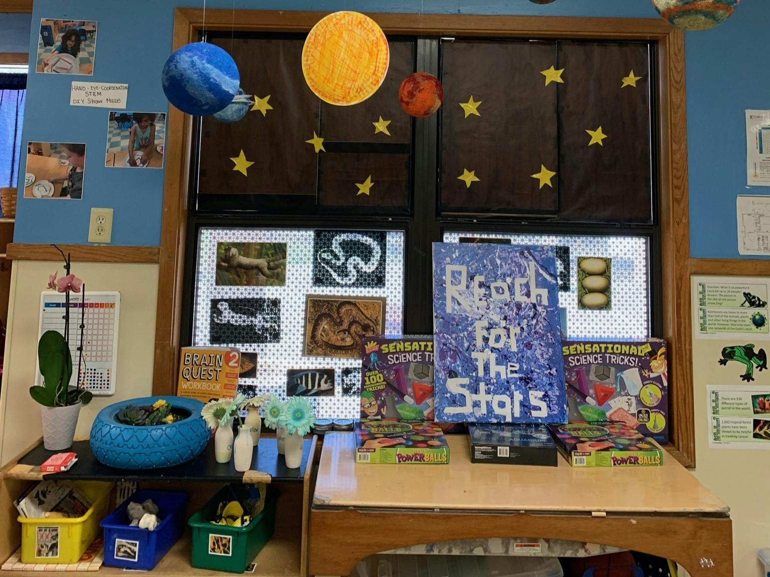 Classroom decorated with planets and stars, with books and games on a table below