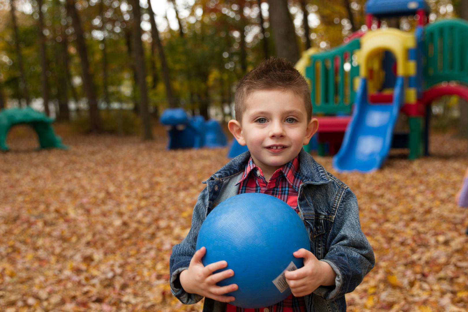Child holding a blue ball on a playground