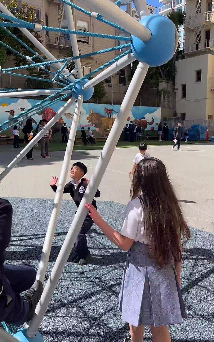 Children playing on a climbing structure in a schoolyard