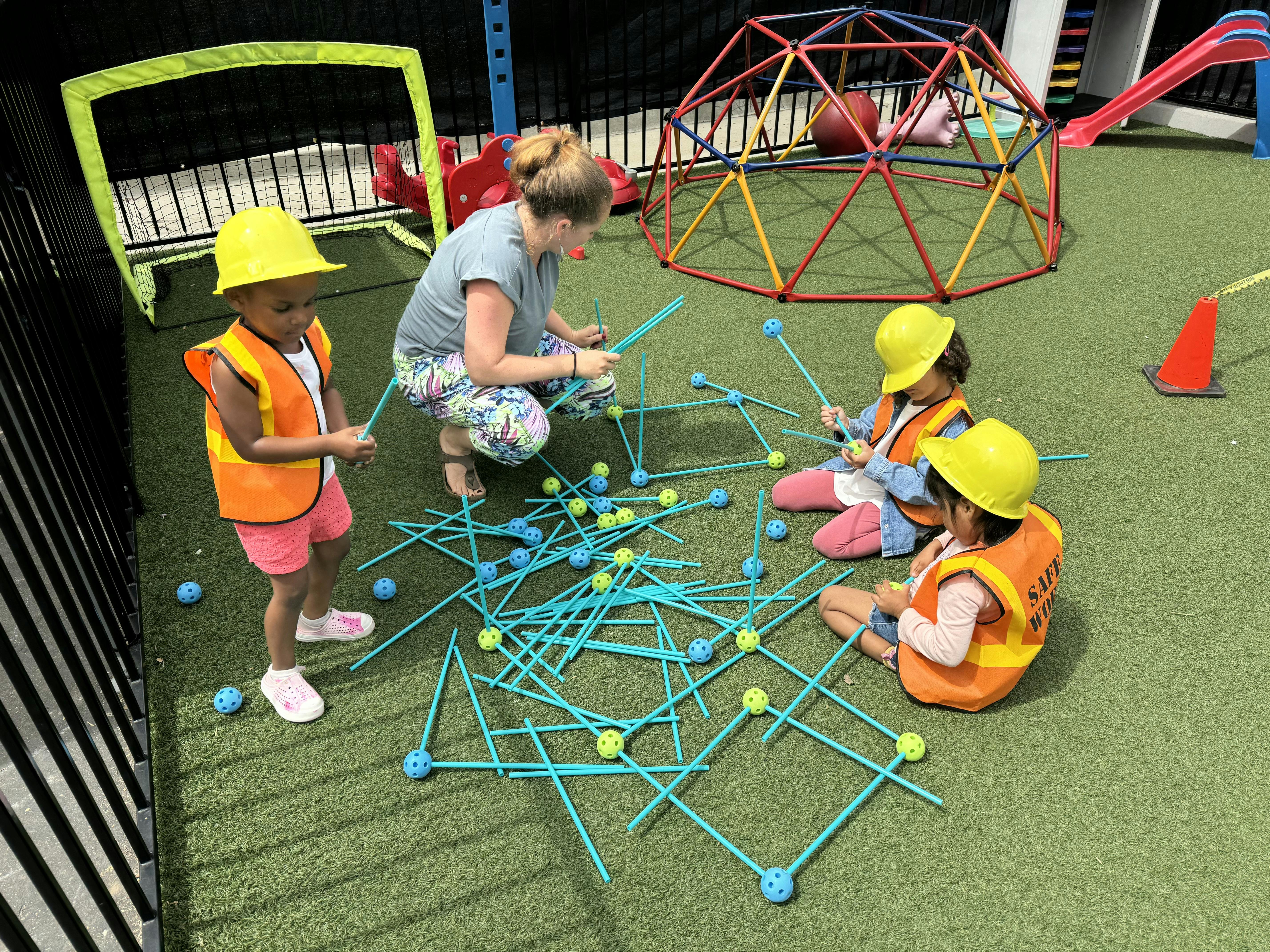Adult and children in hard hats and vests playing with construction toys