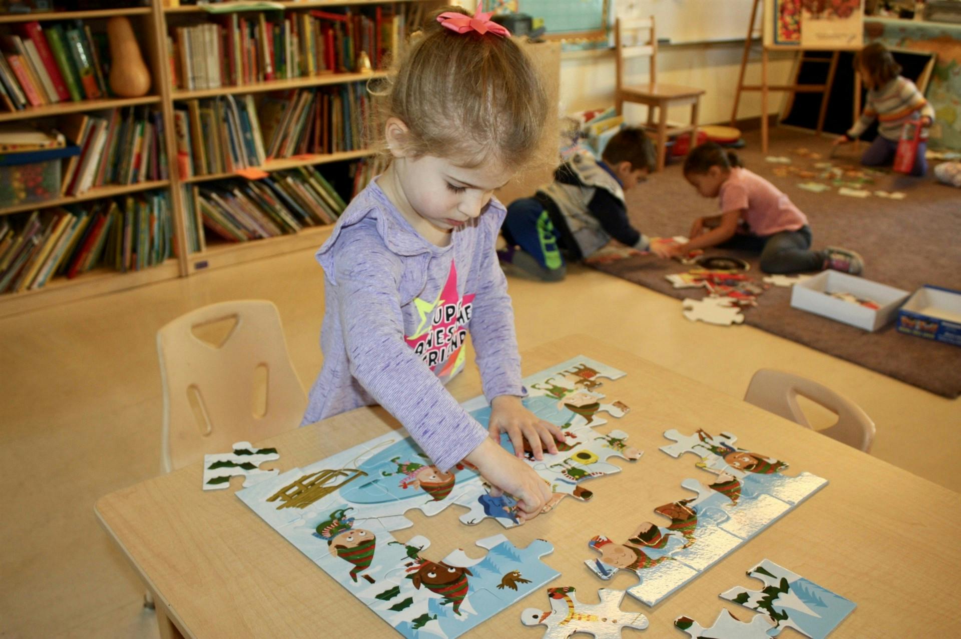 Child assembling a puzzle at a table