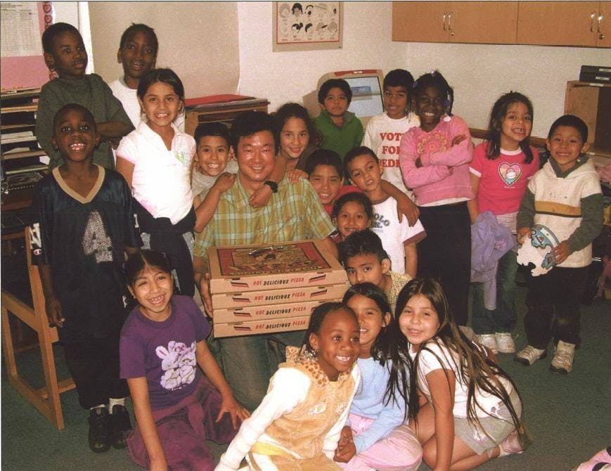 Adult and group of children with pizza boxes