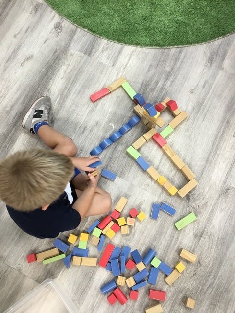 Child playing with colorful building blocks on the floor