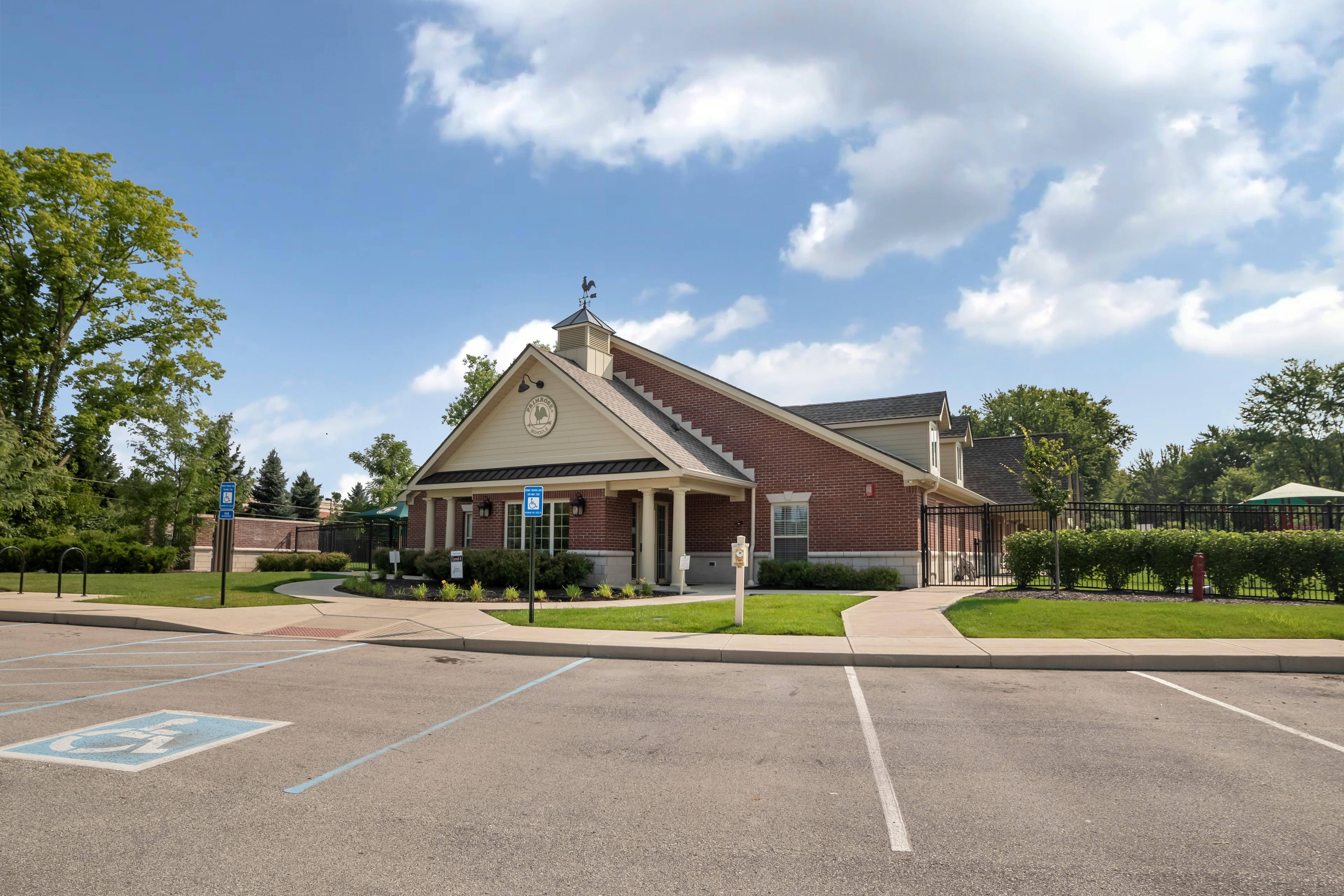 Brick building with a weather vane on the roof next to a parking lot