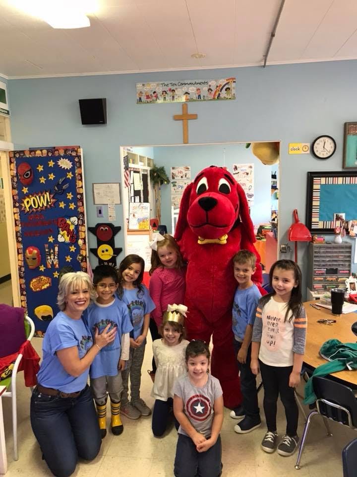 Person in a red dog costume with an adult and several children in a classroom
