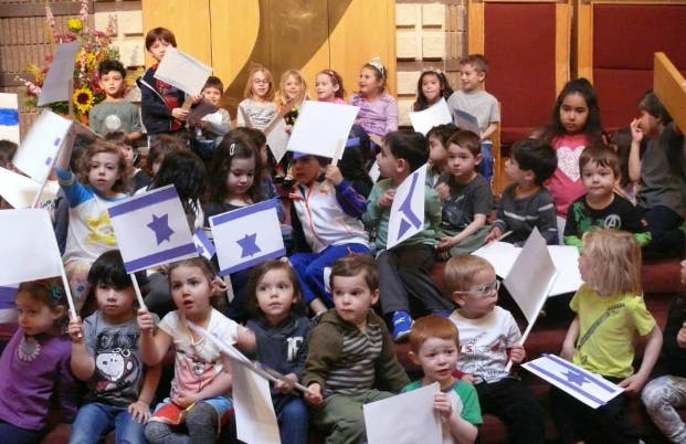 Many children holding small flags with a blue star and stripes
