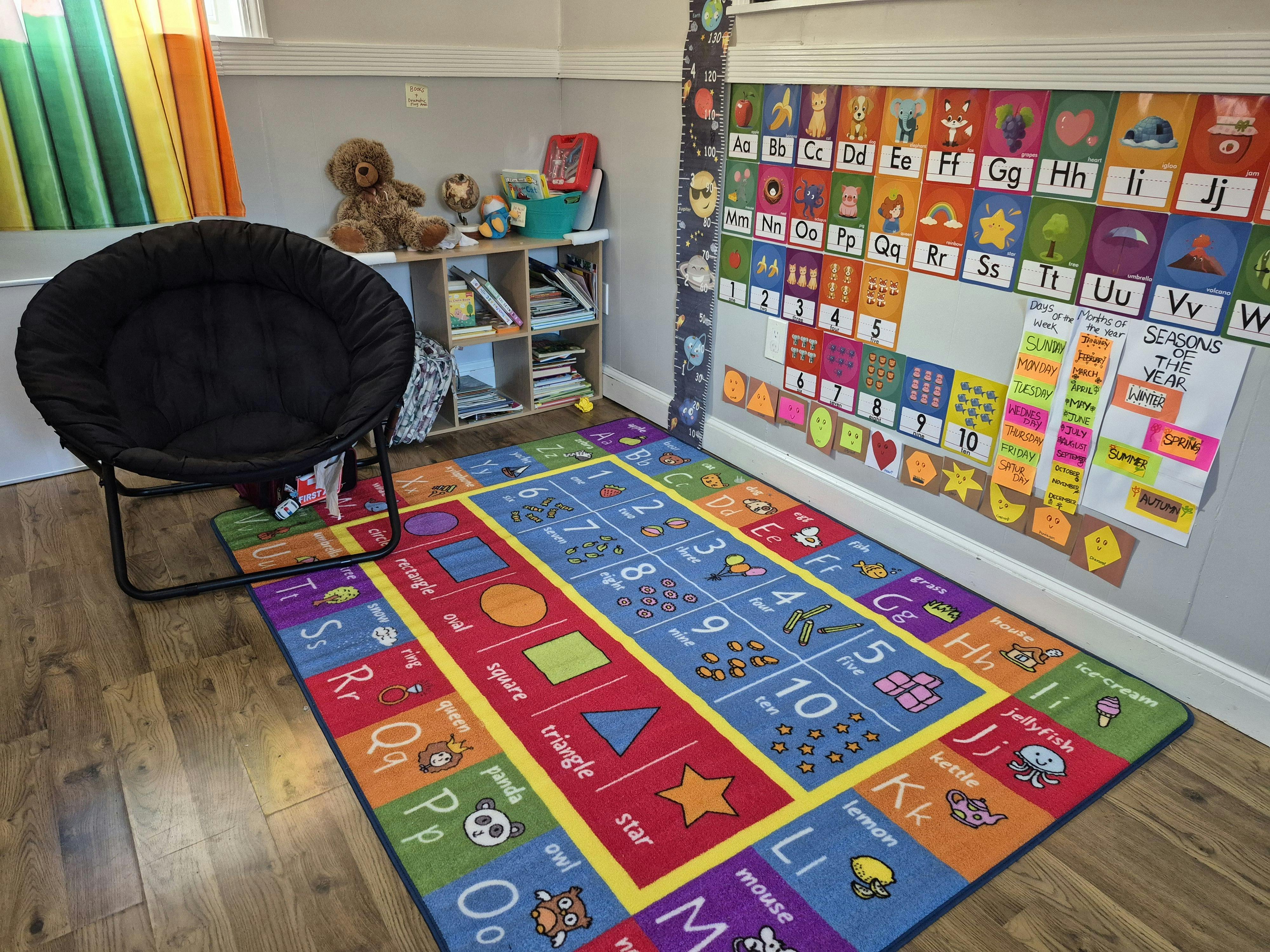 Colorful alphabet and numbers rug in a classroom with a black chair