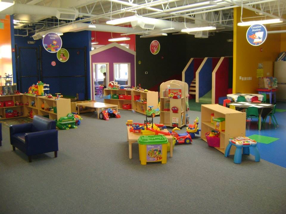 Indoor play area with colorful walls, playhouses, and various toys
