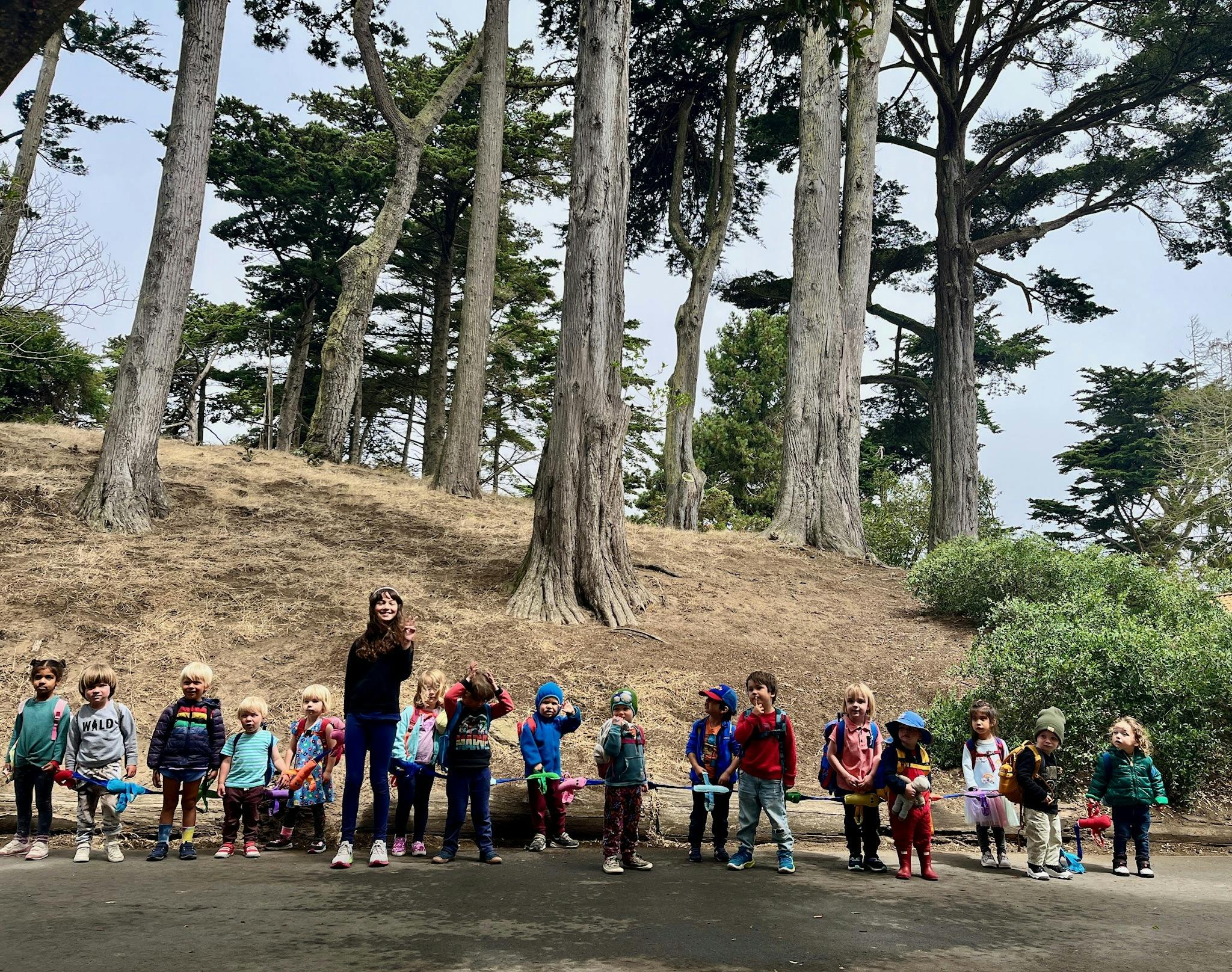 Adult and children standing in front of trees on a hill
