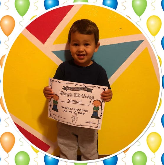 Child holding a "Happy Birthday Samuel" sign