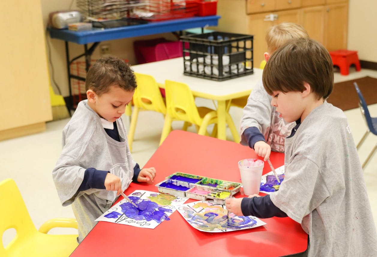 Children painting at a table in a classroom