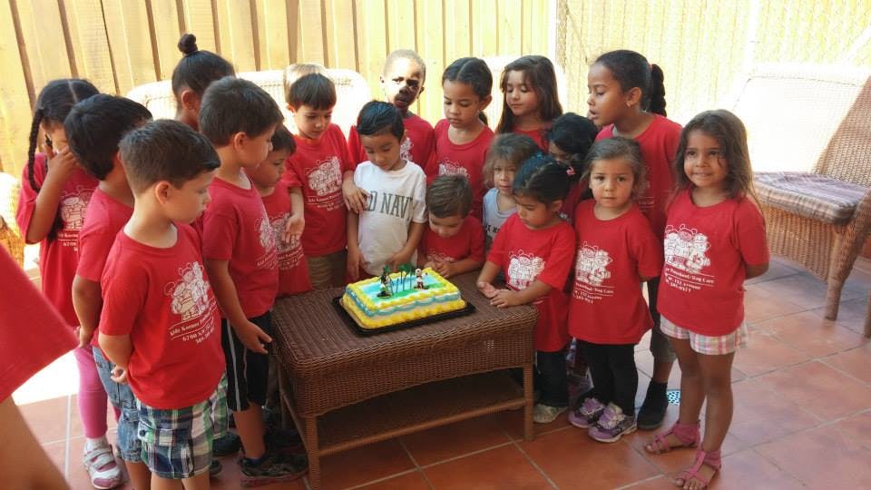 Group of children gathered around a cake on a table