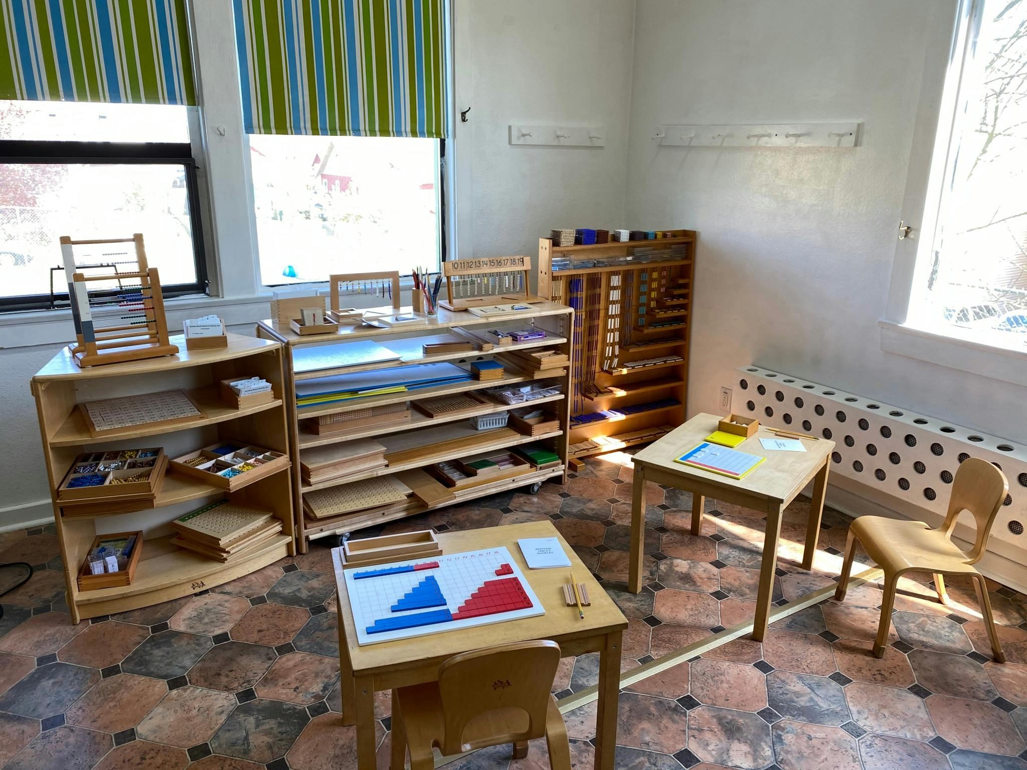 Classroom with wooden shelves, tables, and chairs