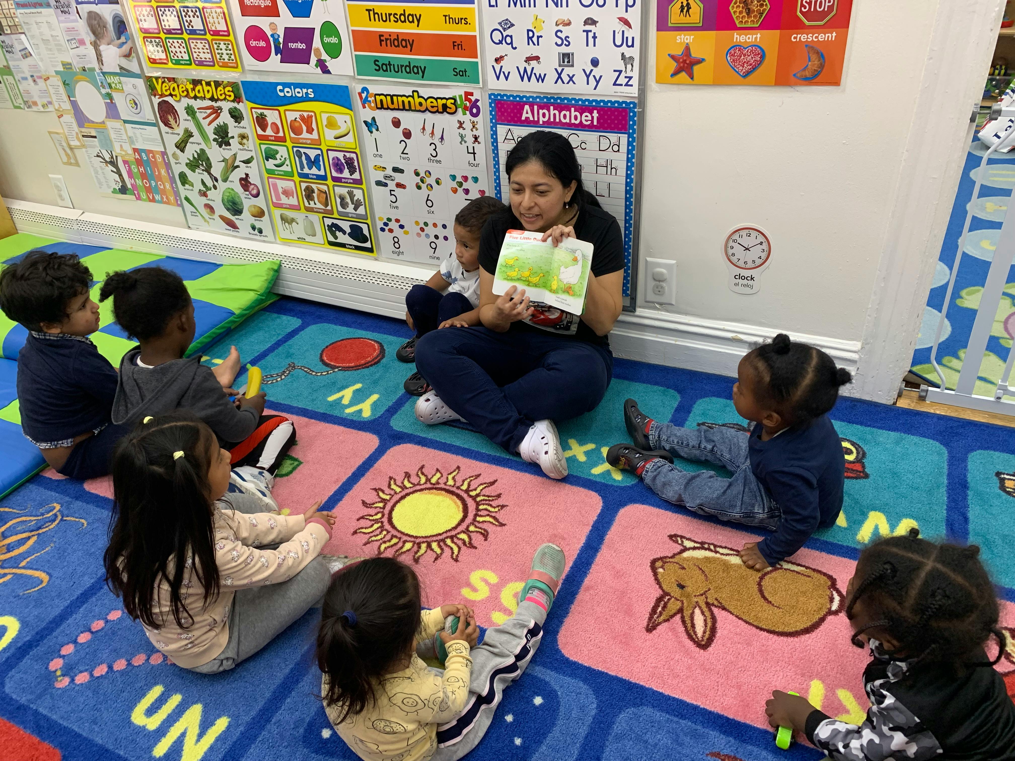 Person reading a book to children in a classroom