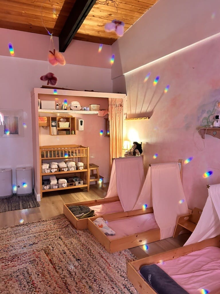 Baby changing station and several toddler beds with canopies in a soft lit room