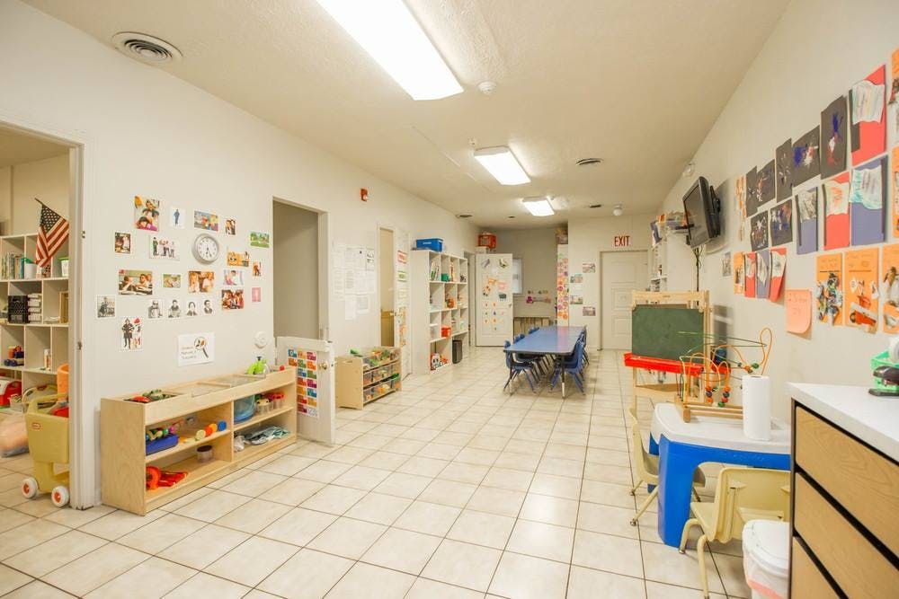 Classroom with tables, chairs, and shelves with toys and art on walls