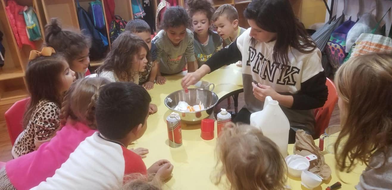 Person mixing ingredients in a bowl with children watching in a classroom