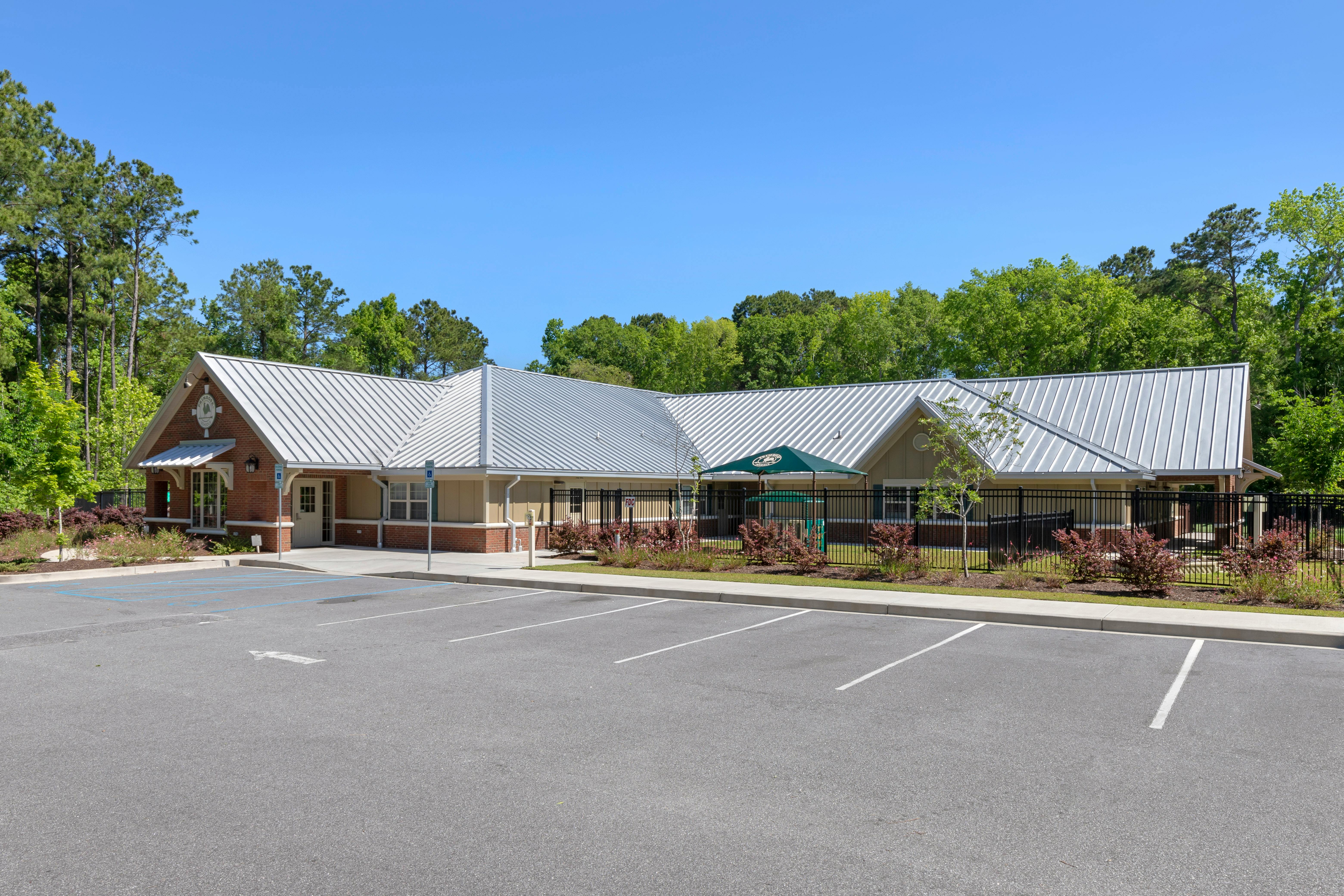 Single-story building with a silver roof, brick and tan walls, and a parking lot