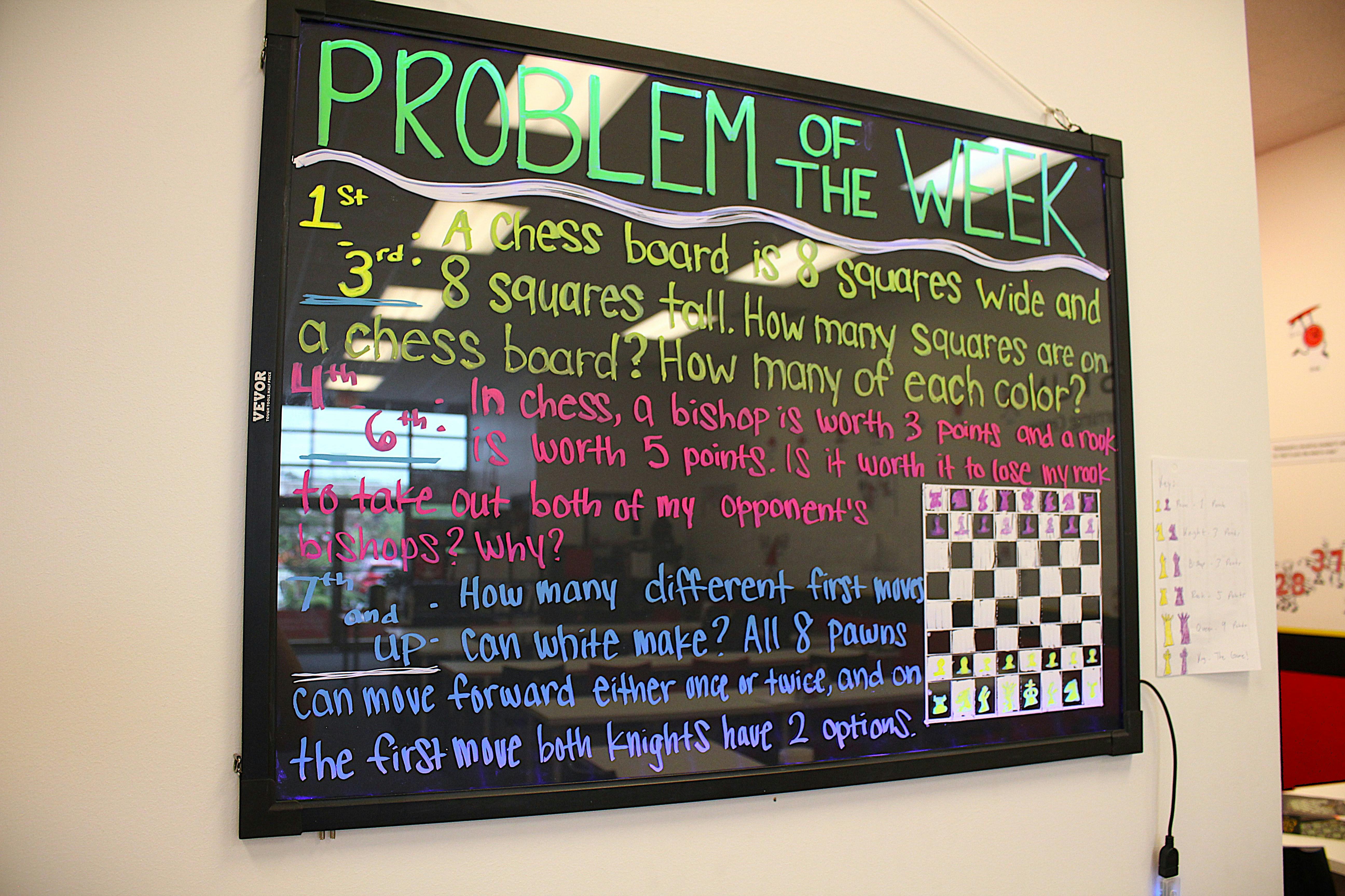 Blackboard with "Problem of the Week" and chess problems written in chalk