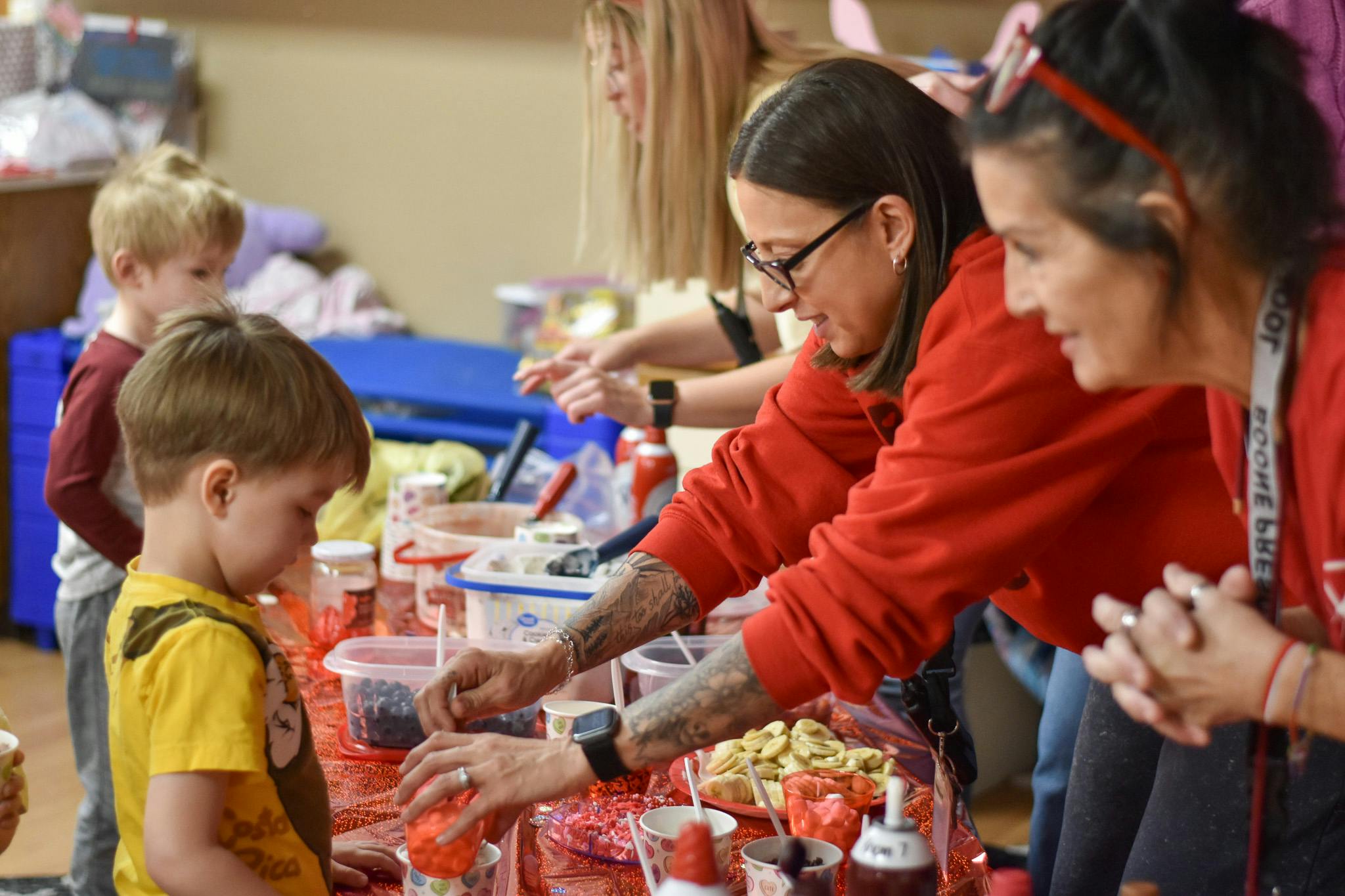 Adults and children preparing food with various toppings at a table