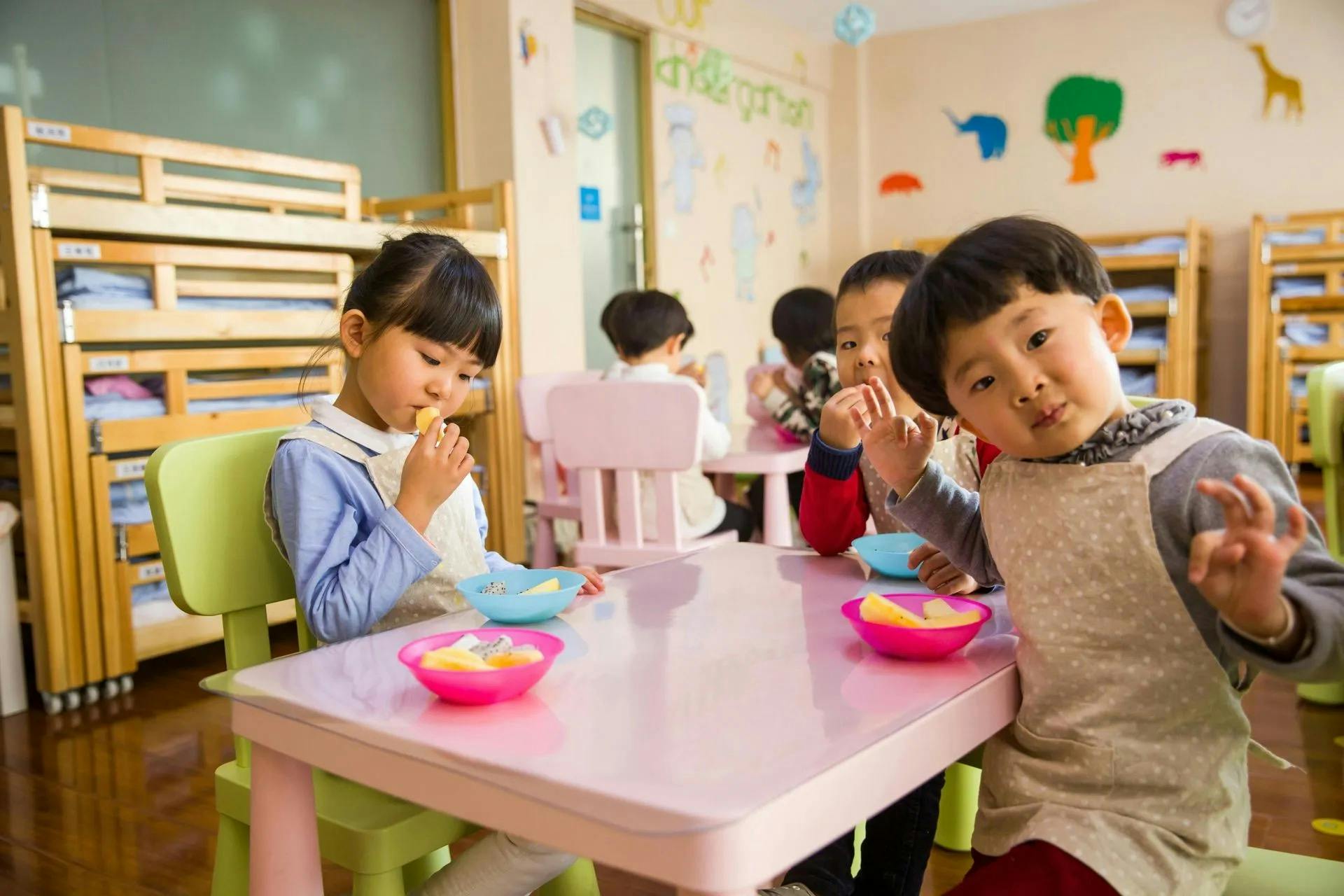 Children sitting at a table eating fruit in a classroom