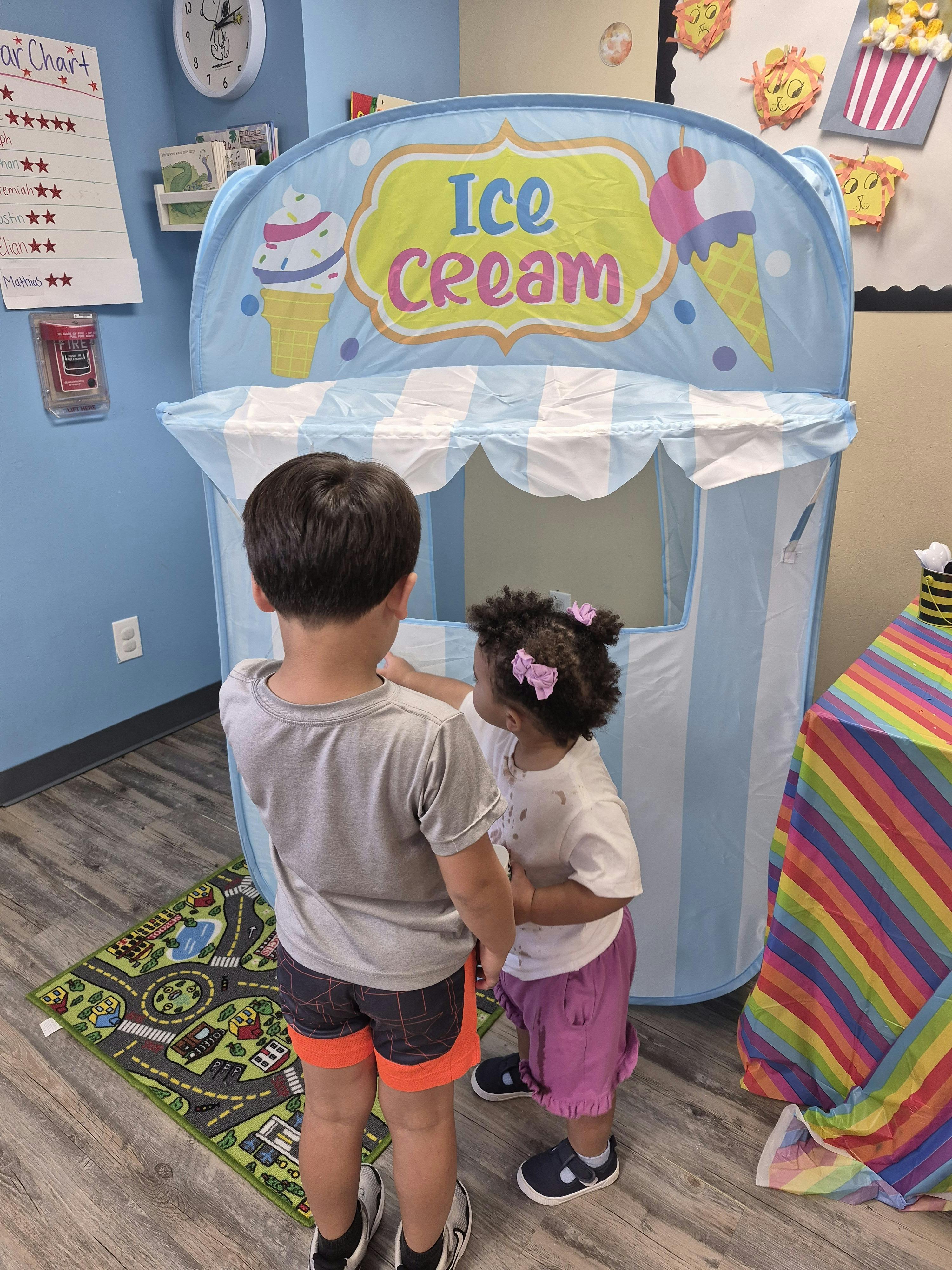Two children playing at an ice cream shop toy stand