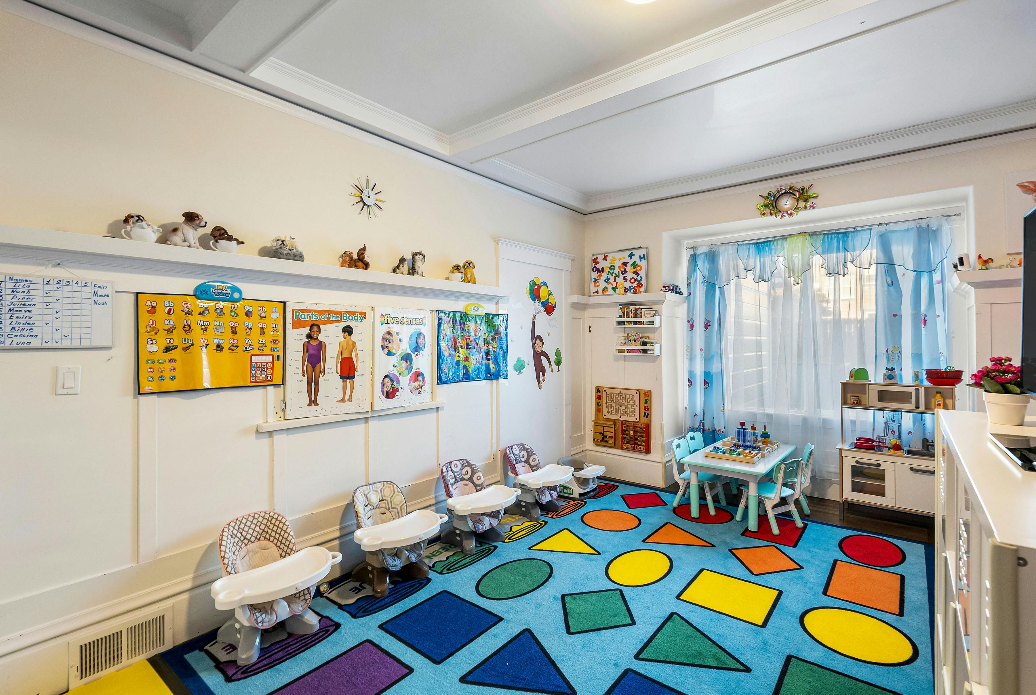 Classroom with colorful rug, small tables, and high chairs