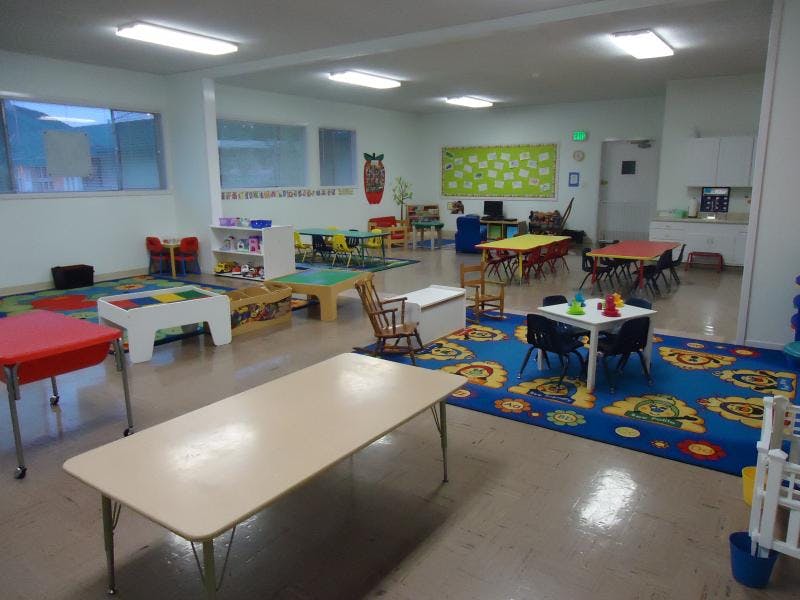 Classroom with small tables, chairs, and colorful rugs