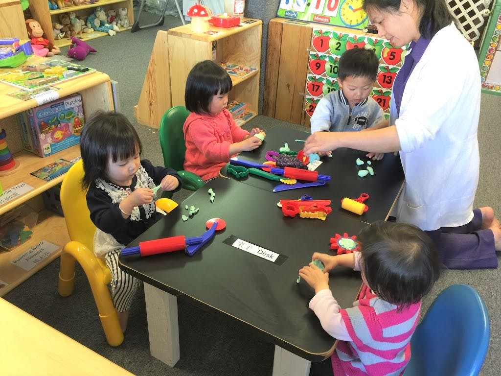 Adult and three children playing with toys at a table