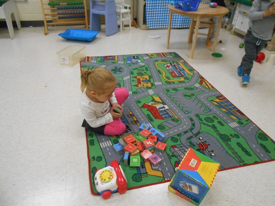 Child playing with blocks on a road map rug