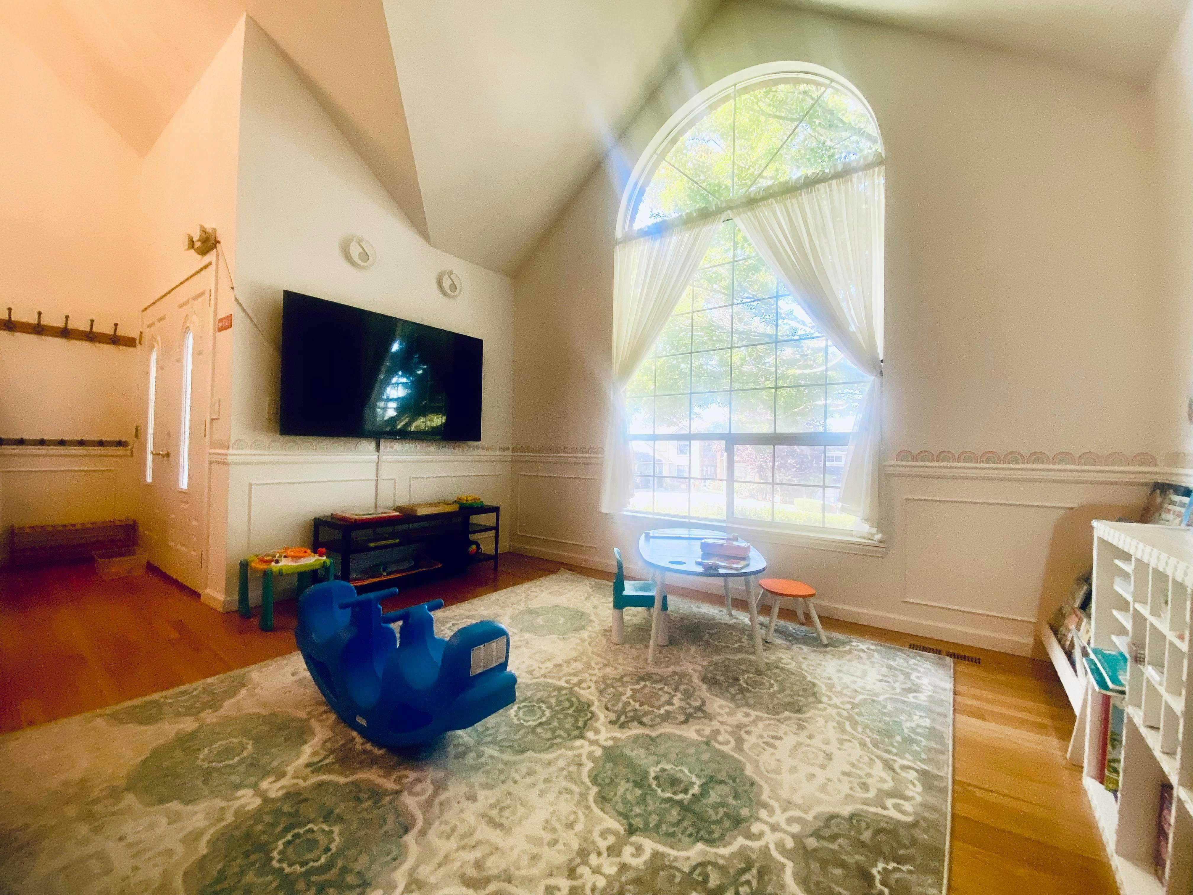 Playroom with a large arched window, television, and child-sized furniture