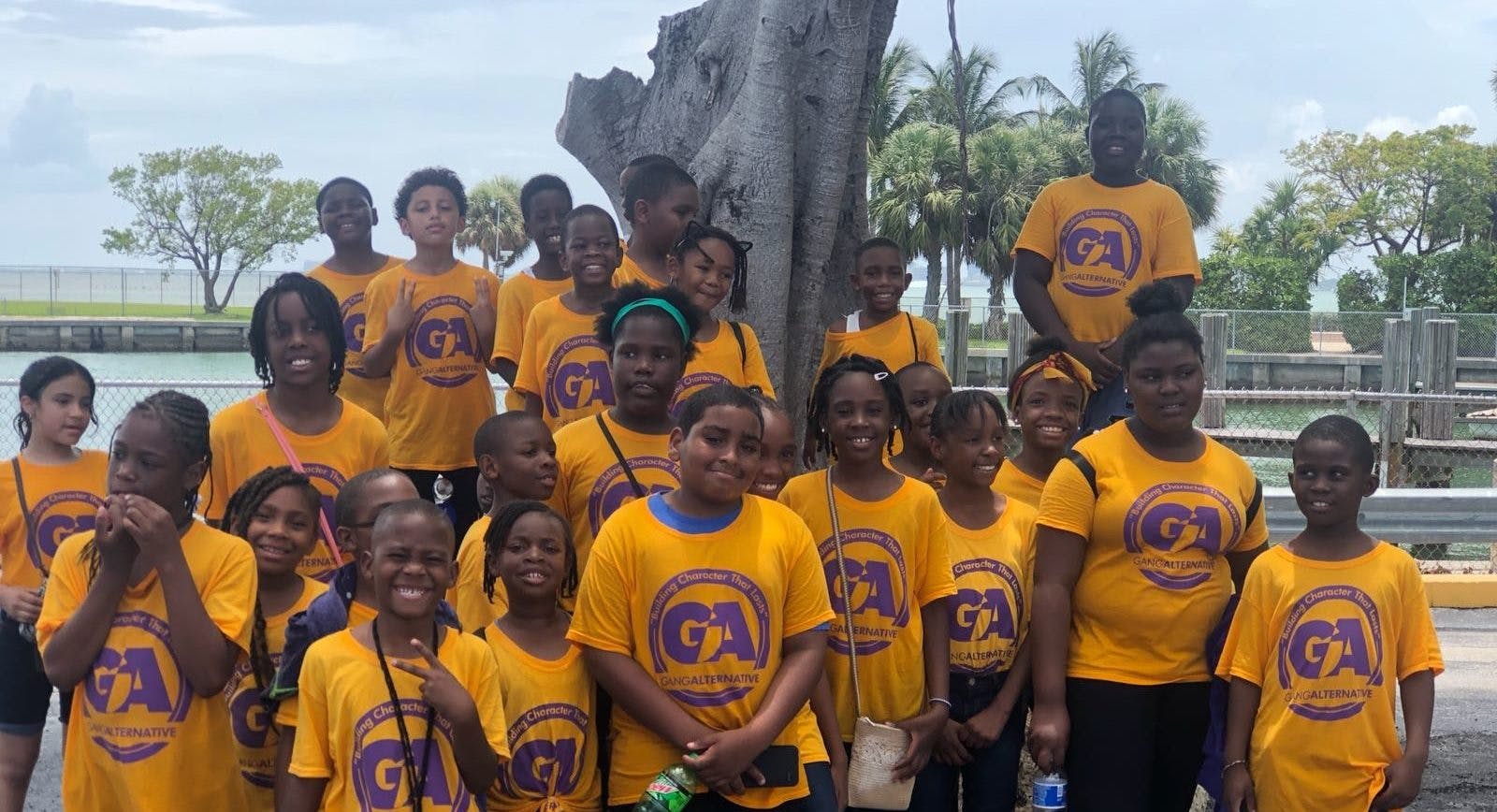 Group of children and adults in matching yellow shirts posing outdoors