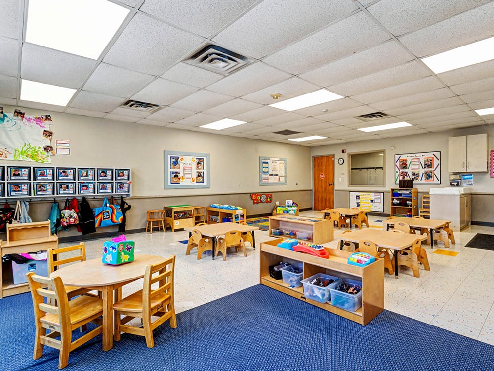 Empty preschool classroom with small tables and chairs